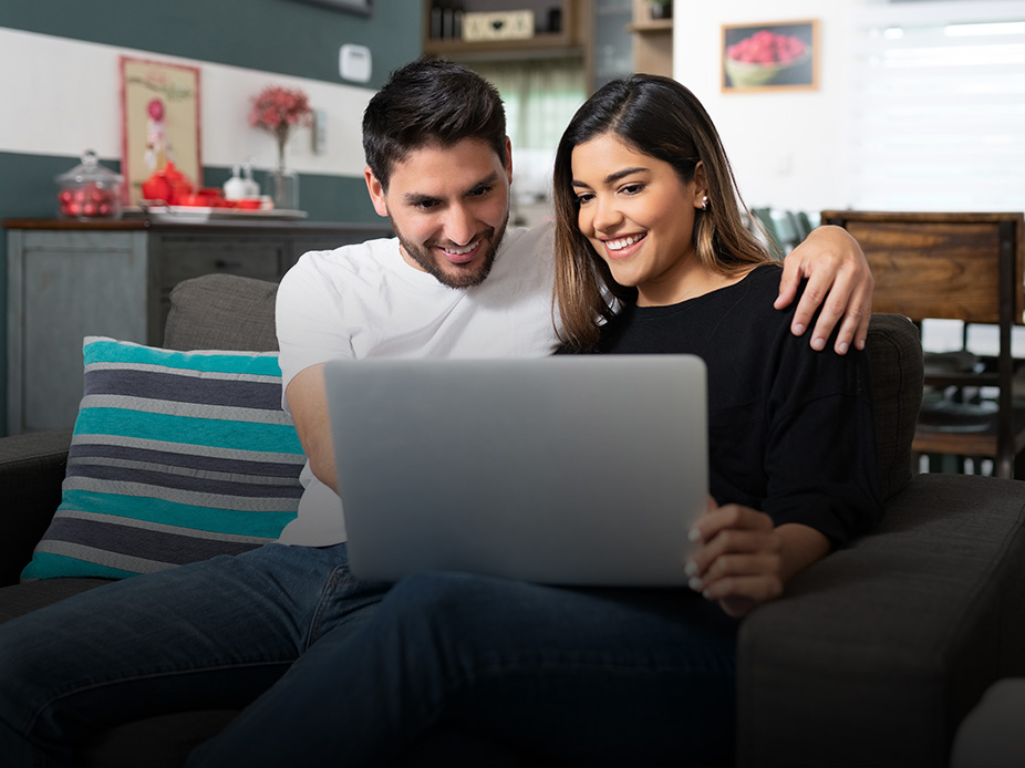 Young, happy couple looking at a laptop.