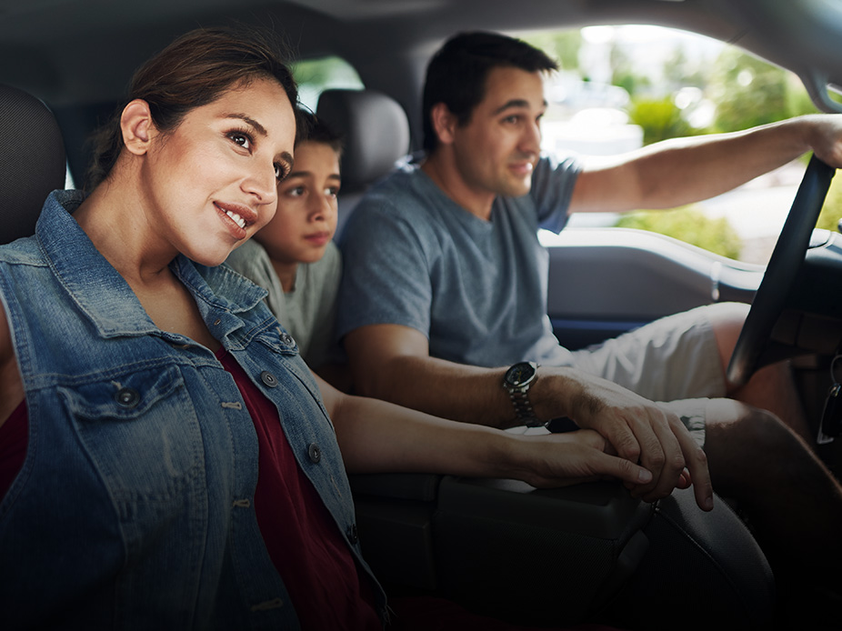 Happy parents driving in a car with their son.
